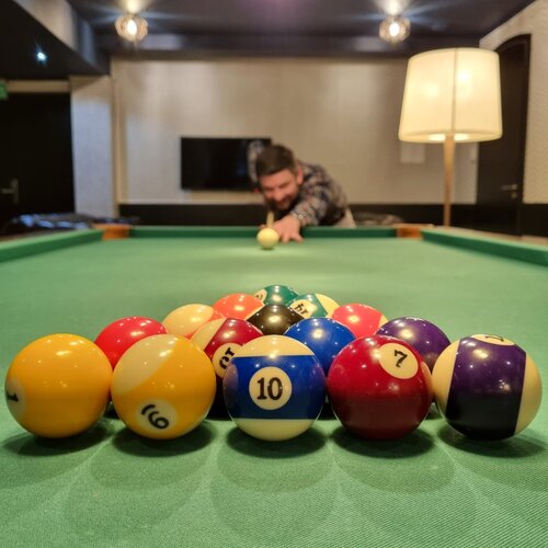 아늑한 호텔 게임룸의 당구대, 정렬된 당구공과 큐로 샷을 준비하는 투숙객
